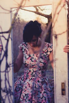 一名身穿花卉连衣裙的女子在黄金时段的户外场景中，手持一个质朴的门框
