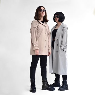Two models in trench coats against a white studio wall, photo by Pegah Sharifi on Pexels