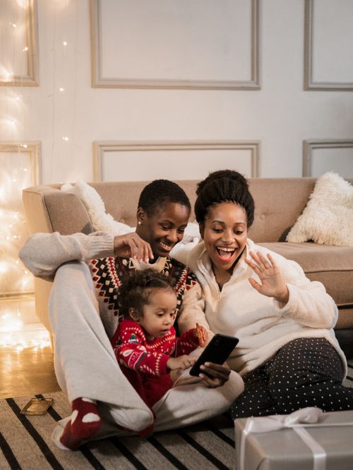 Free Cheerful family enjoying a video call with loved ones during a cozy Christmas gathering indoors. Stock Photo