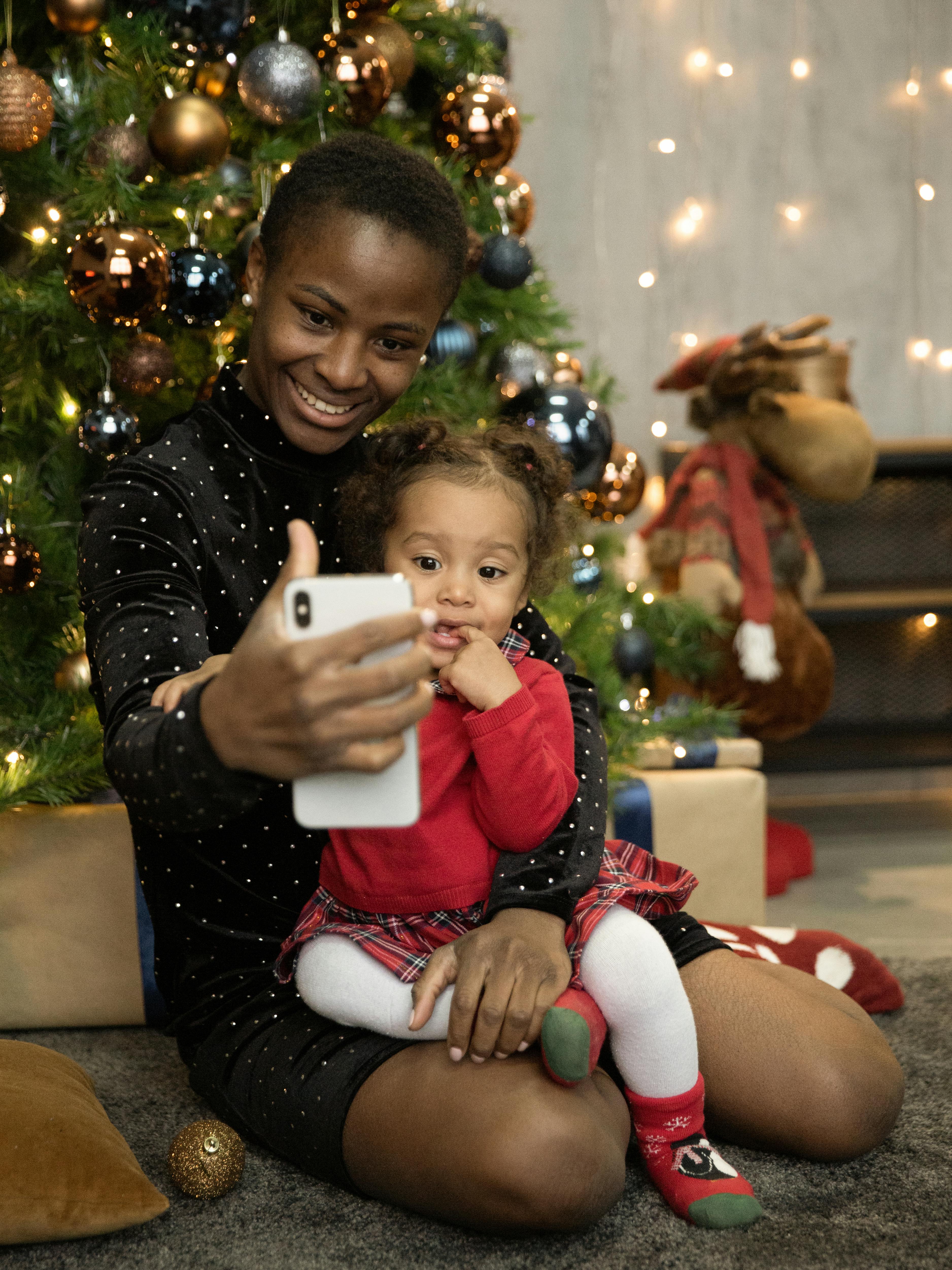 woman in black long sleeve shirt holding baby and a smartphone