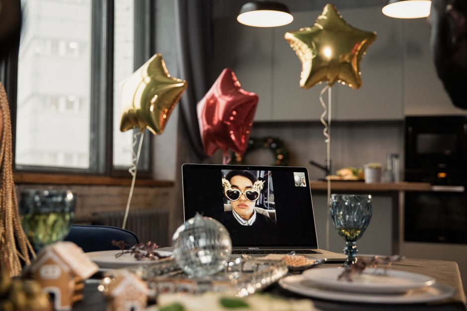 A lively Christmas party setup with star balloons and a laptop displaying a video call, embracing virtual festivities.