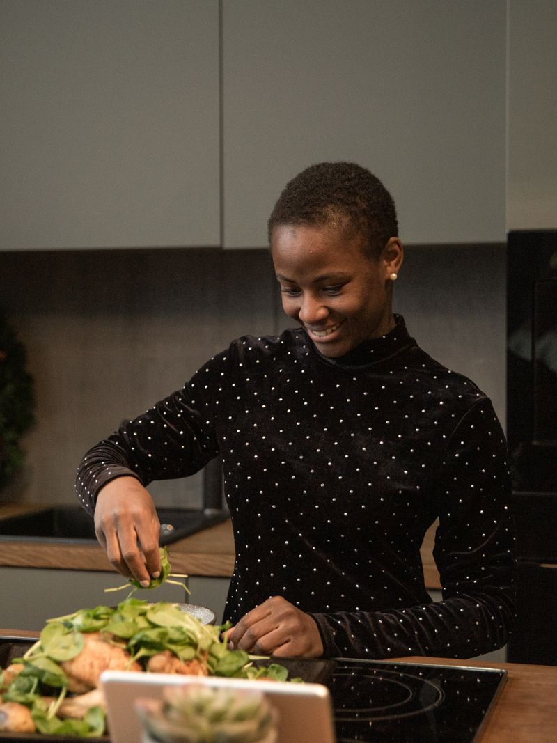 A Black woman prepares a fresh salad in her kitchen. What and how you eat is one of the most effective levers for easing acid reflux and GERD.