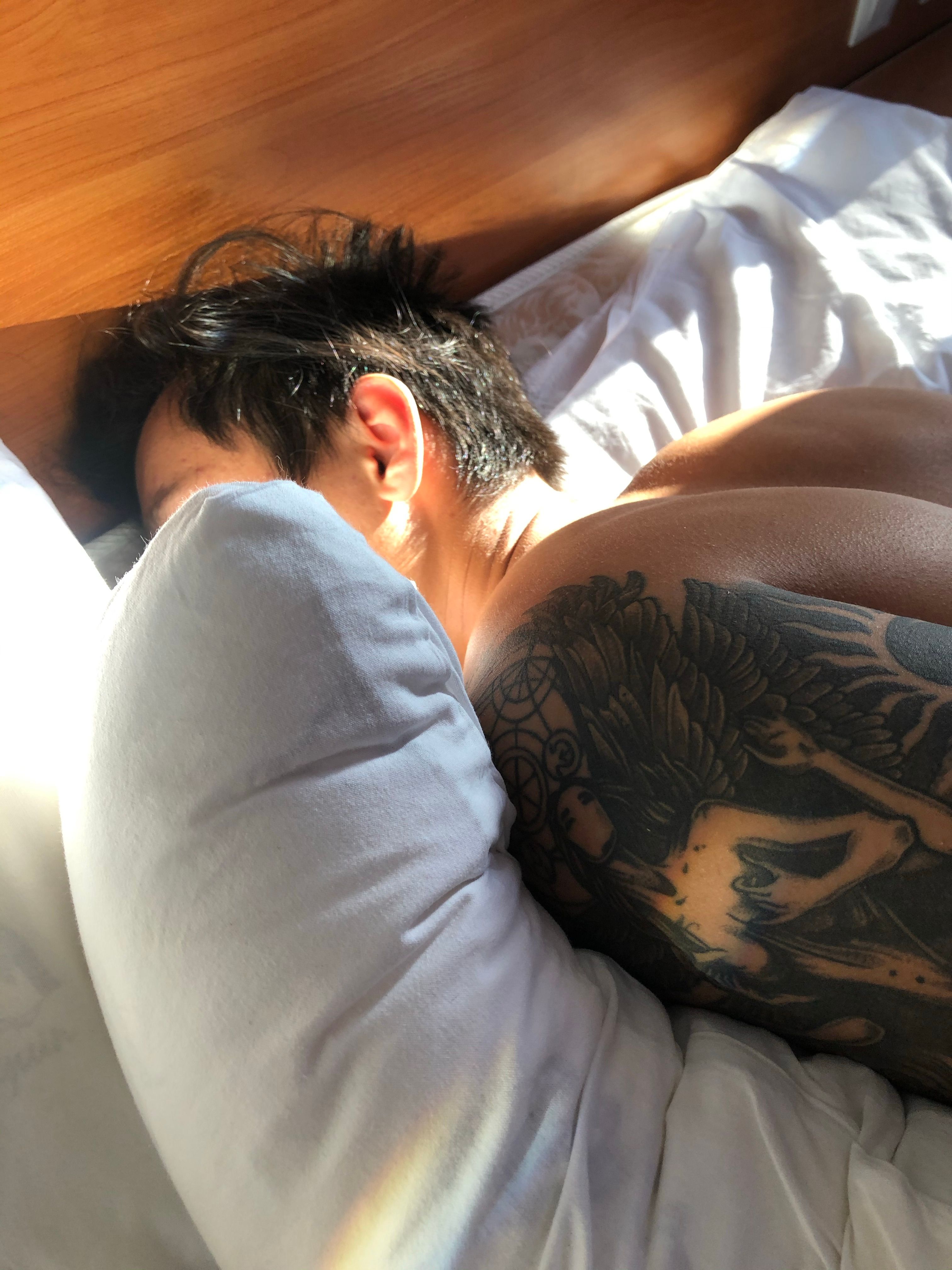 Close-up of a shirtless man sleeping, illuminated by sunlight.