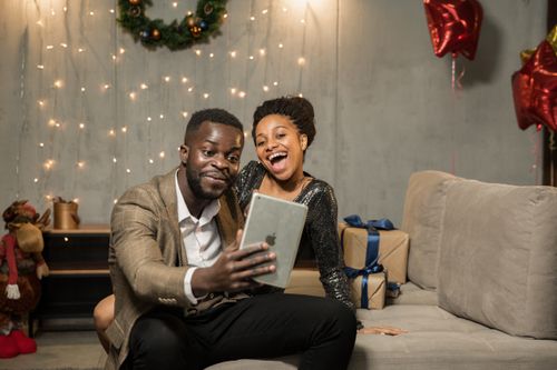 Free A joyful couple at home, video calling during a festive holiday celebration with gifts and decorations. Stock Photo