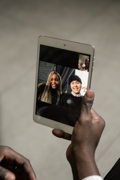 Free Person Holding White Ipad Displaying Man And Woman Stock Photo