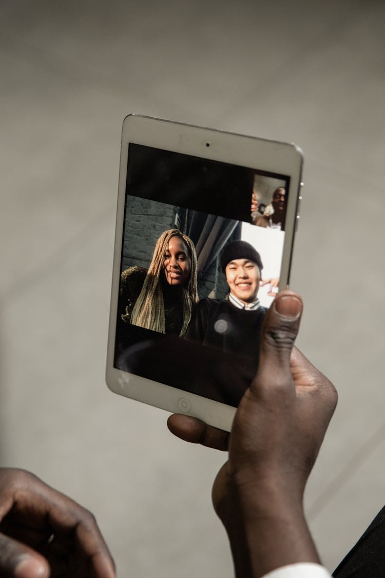 Person Holding White Ipad Displaying Man And Woman