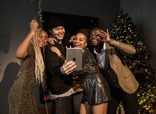 Free Group of young adults enjoying a festive virtual Christmas party, posing for a selfie. Stock Photo