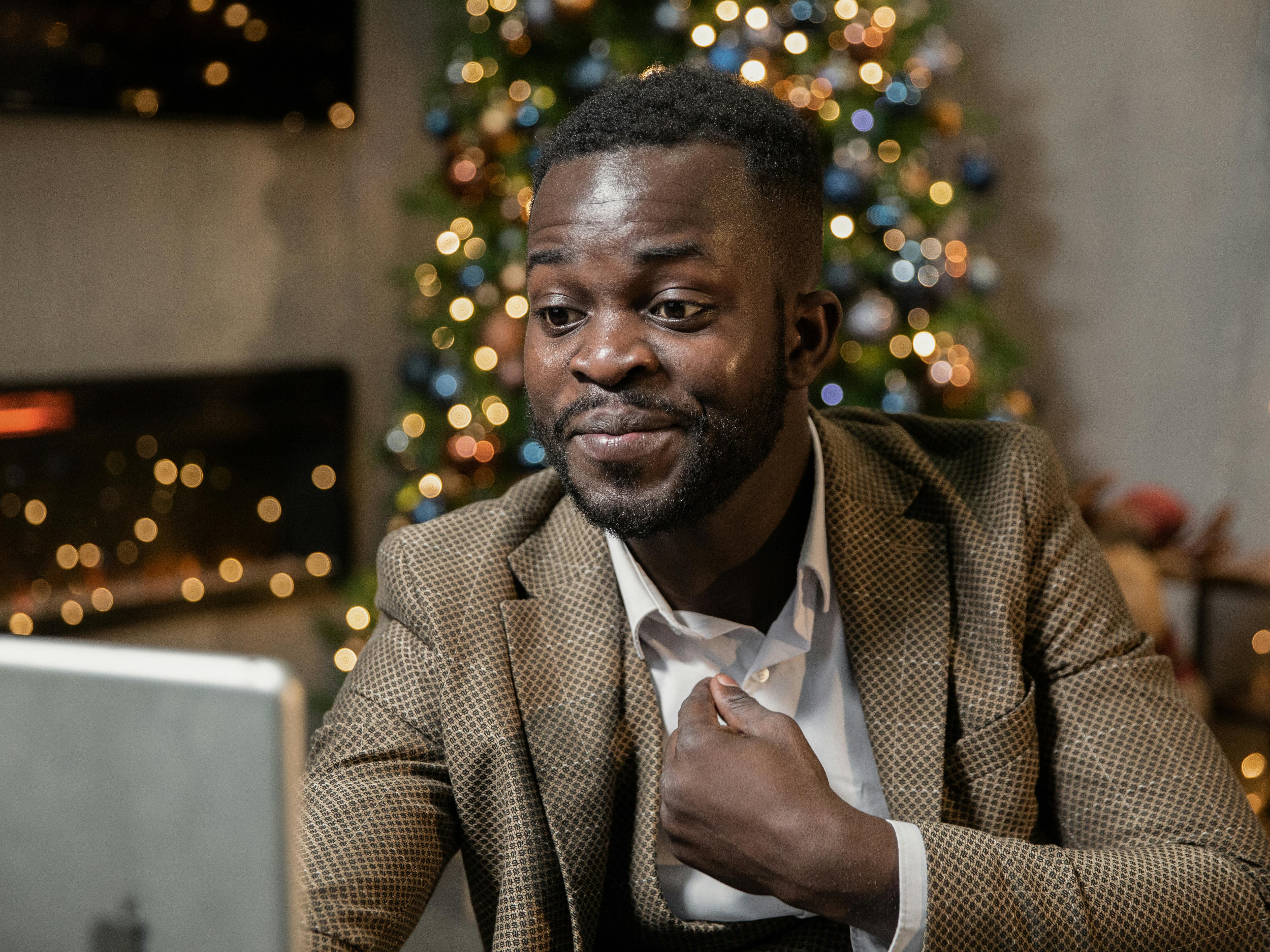 一名开朗的西装男子在家中举行圣诞聚会，正通过视频通话享受节日