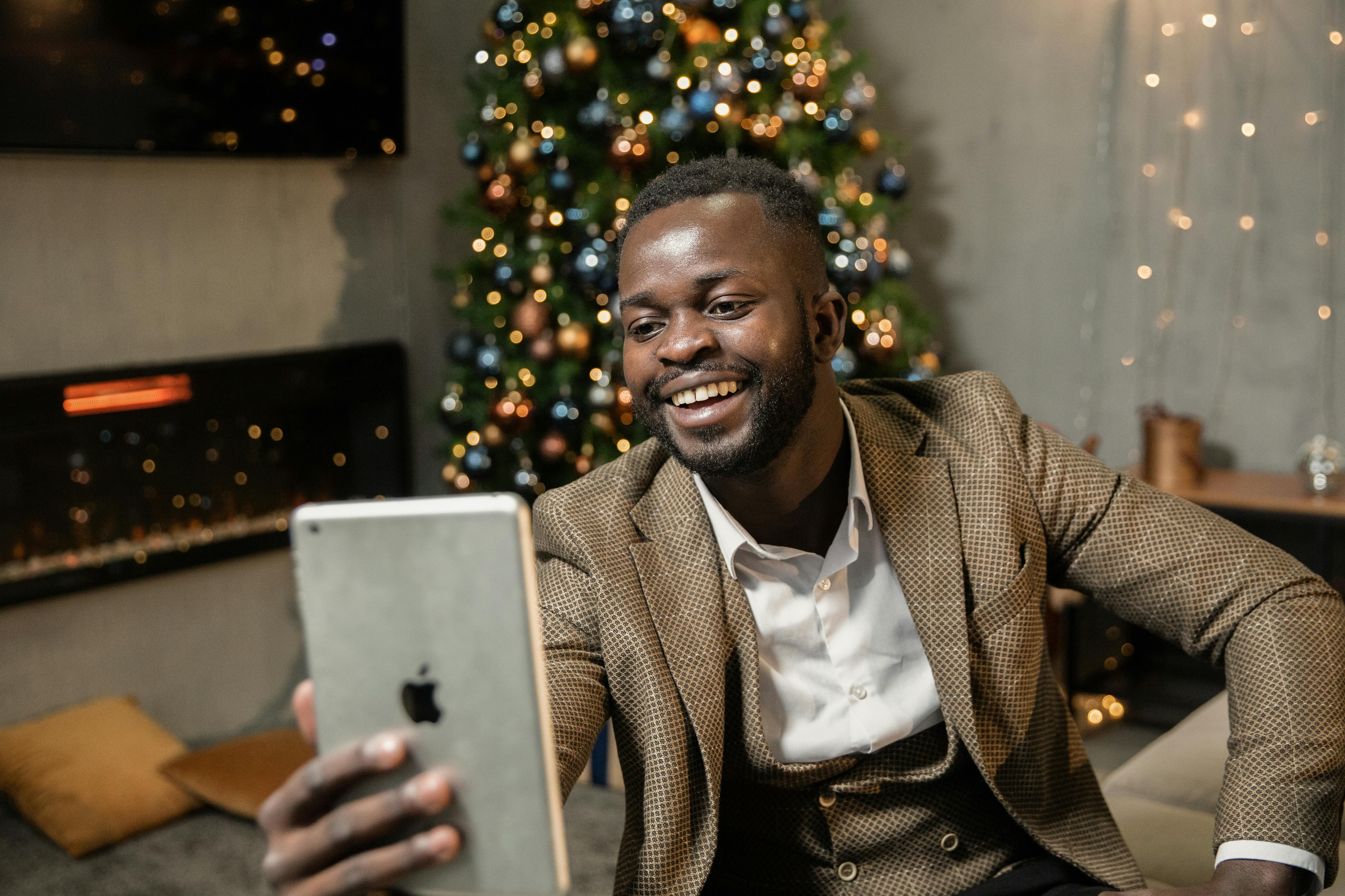 man in brown suit jacket holding silver ipad