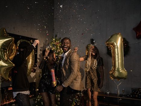 一群朋友在室内用五彩纸屑和气球庆祝新年，洋溢着欢乐与幸福