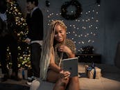 在家中的圣诞派对上，一个女人正微笑着用平板电脑视频通话