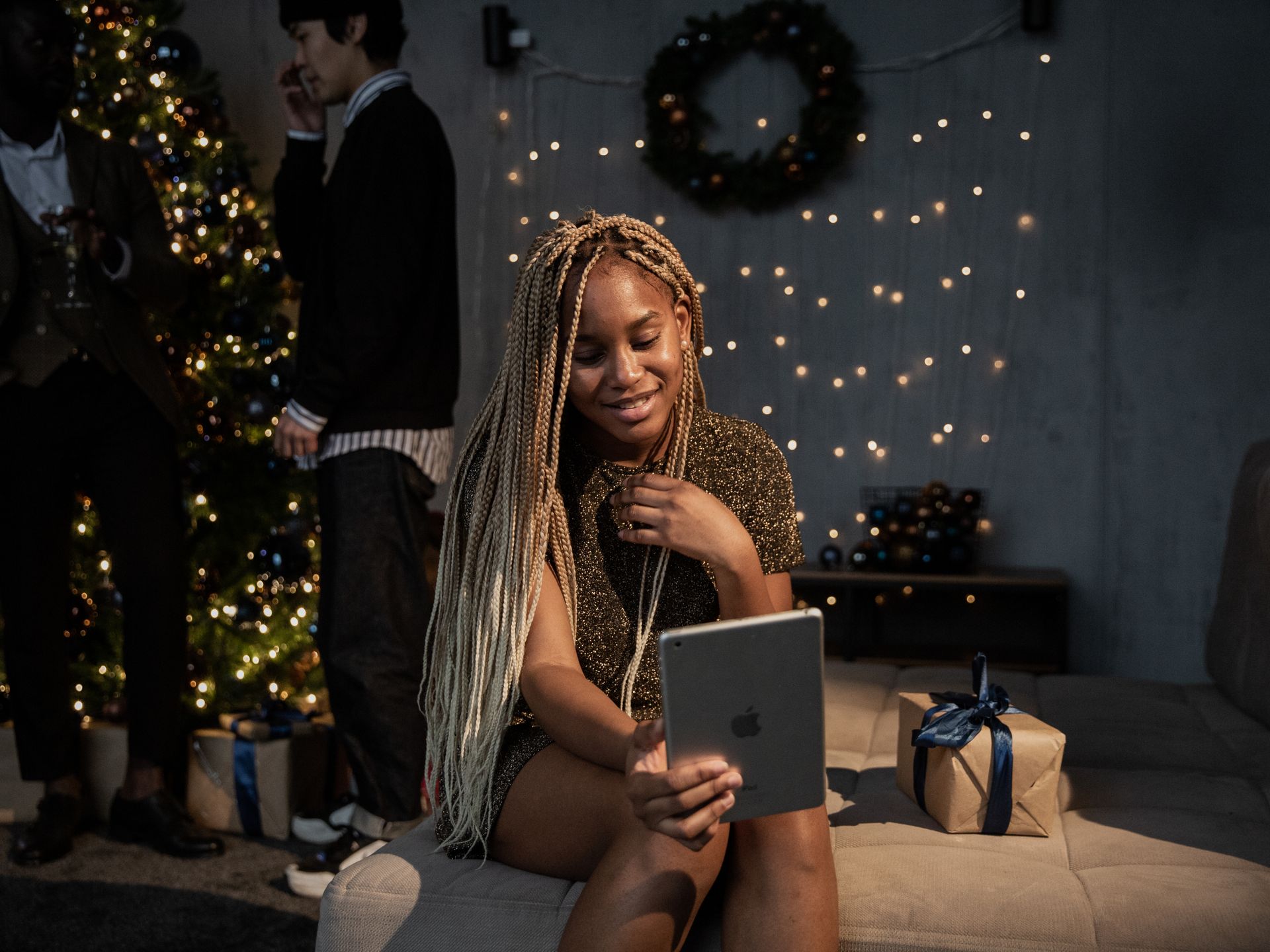 Smiling woman video calling on a tablet during a Christmas party at home.