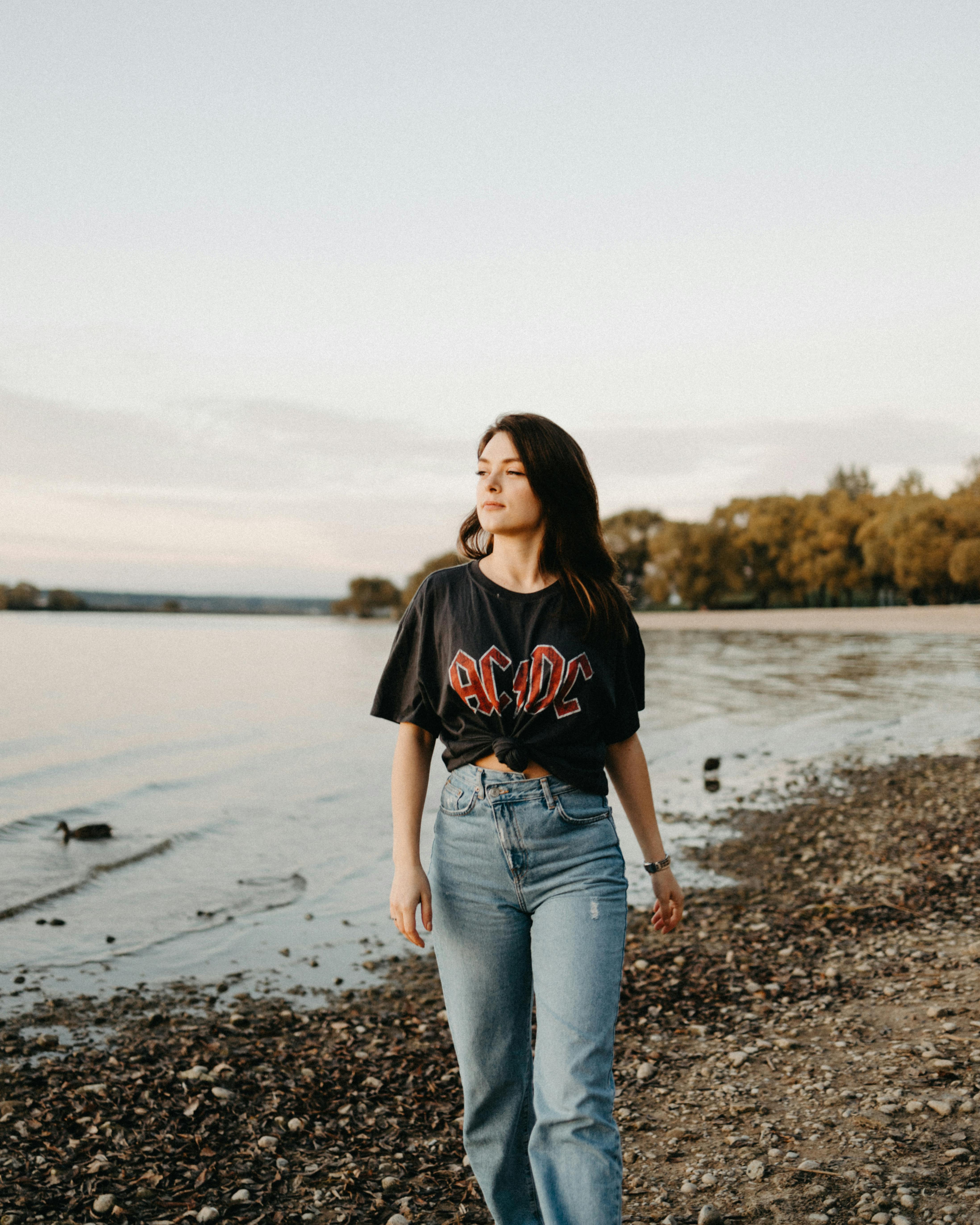 Woman enjoying a peaceful walk by the lakeside during the day. Serene and relaxed atmosphere.