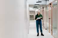 Woman in Green Long Sleeve Shirt and Blue Denim Jeans Standing on Hallway