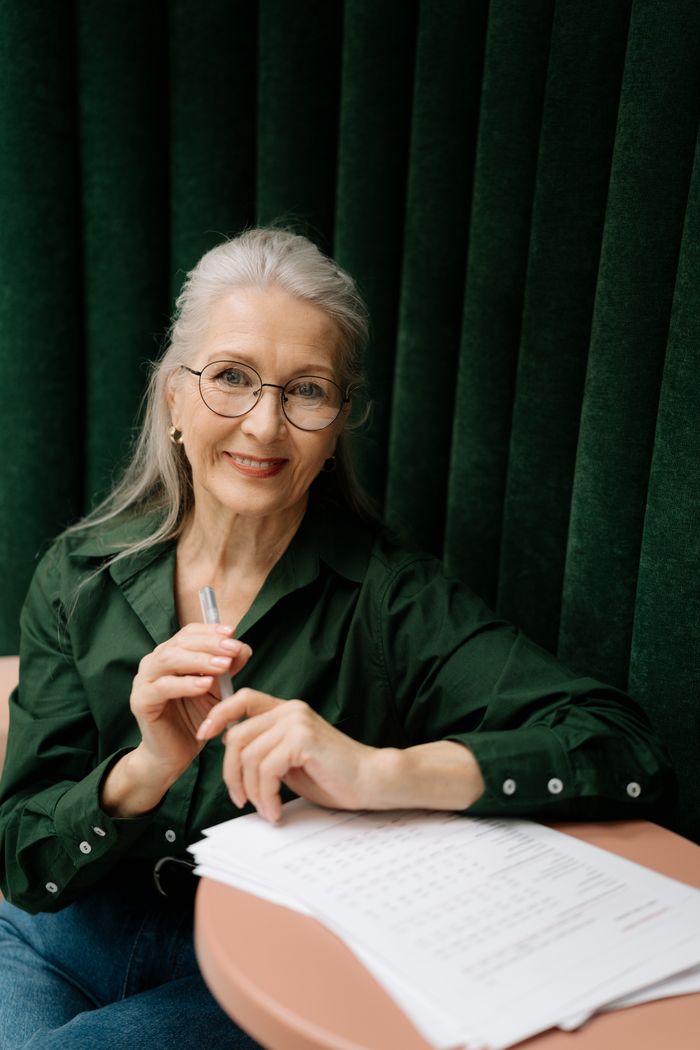 Clara writing notes at a table in a green blouse