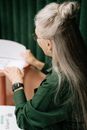 一位灰发的高级女性在办公室内检查文书工作