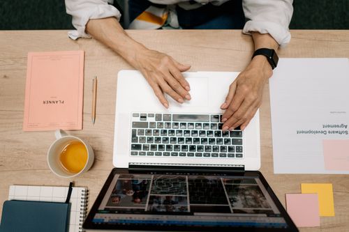 Free Top view of a tidy workspace with laptop, papers, planner, and coffee. Stock Photo