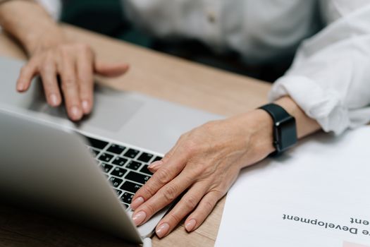 A close-up image of hands with manicured nails typing on a laptop keyboard, showcasing modern workspace.