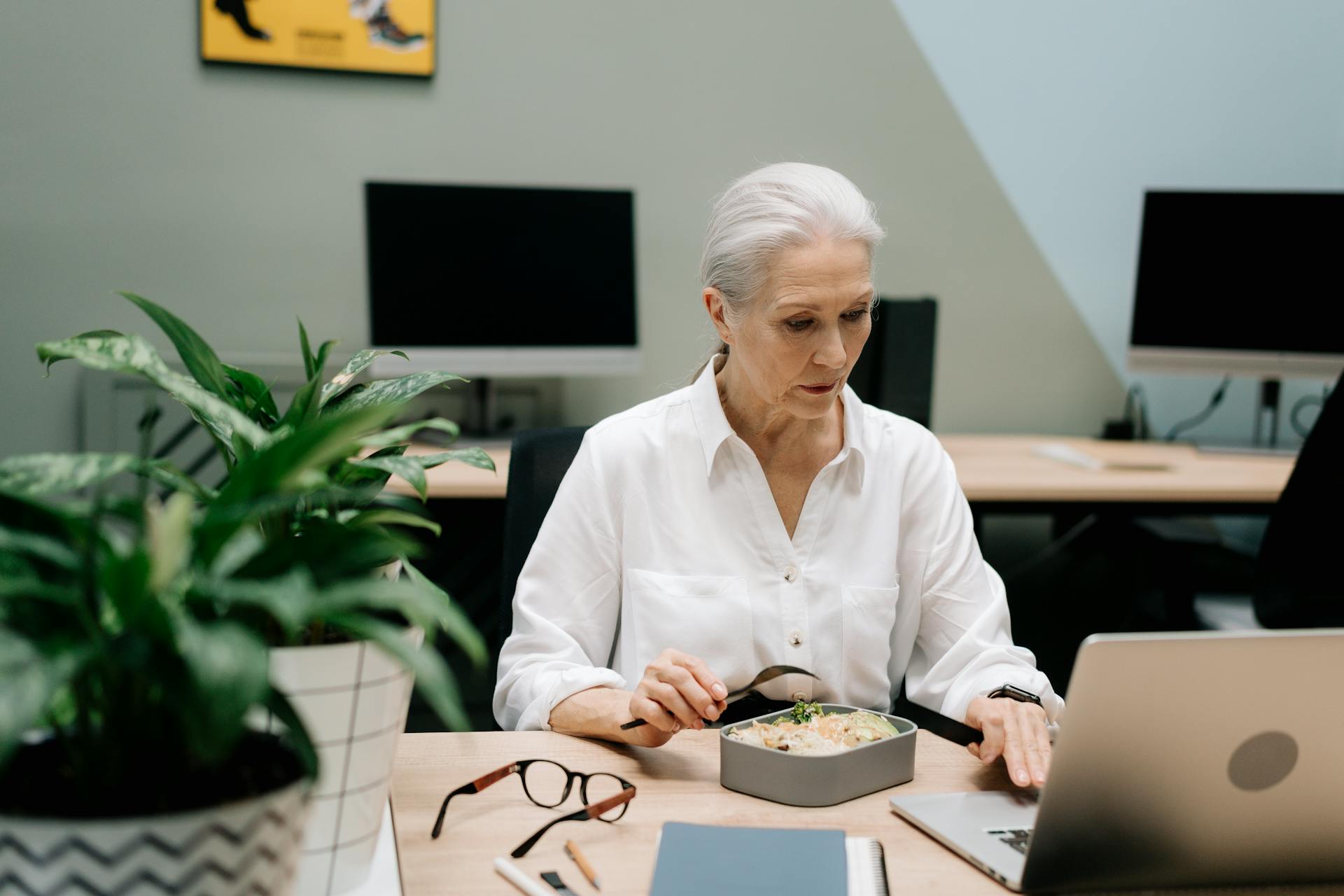 Elderly Woman Eating While Working