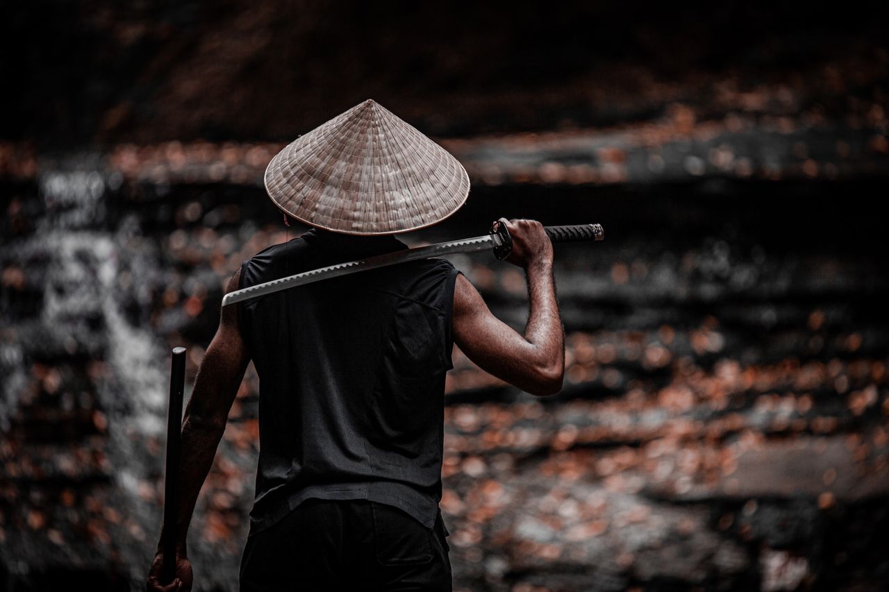 a person with a conical hat holding a sword creating a mysterious warr