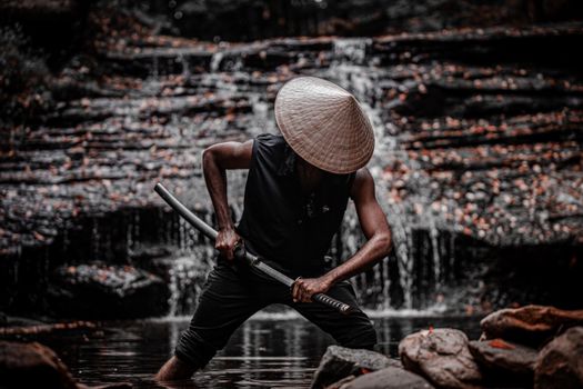 A powerful image of a samurai warrior in traditional attire, standing by a waterfall with a sword.