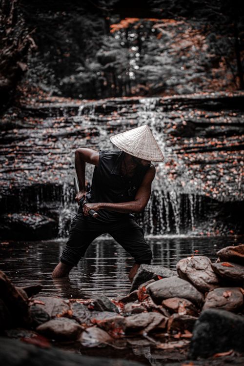Free A samurai figure in traditional attire stands by a waterfall, embodying ancient Japanese culture. Stock Photo