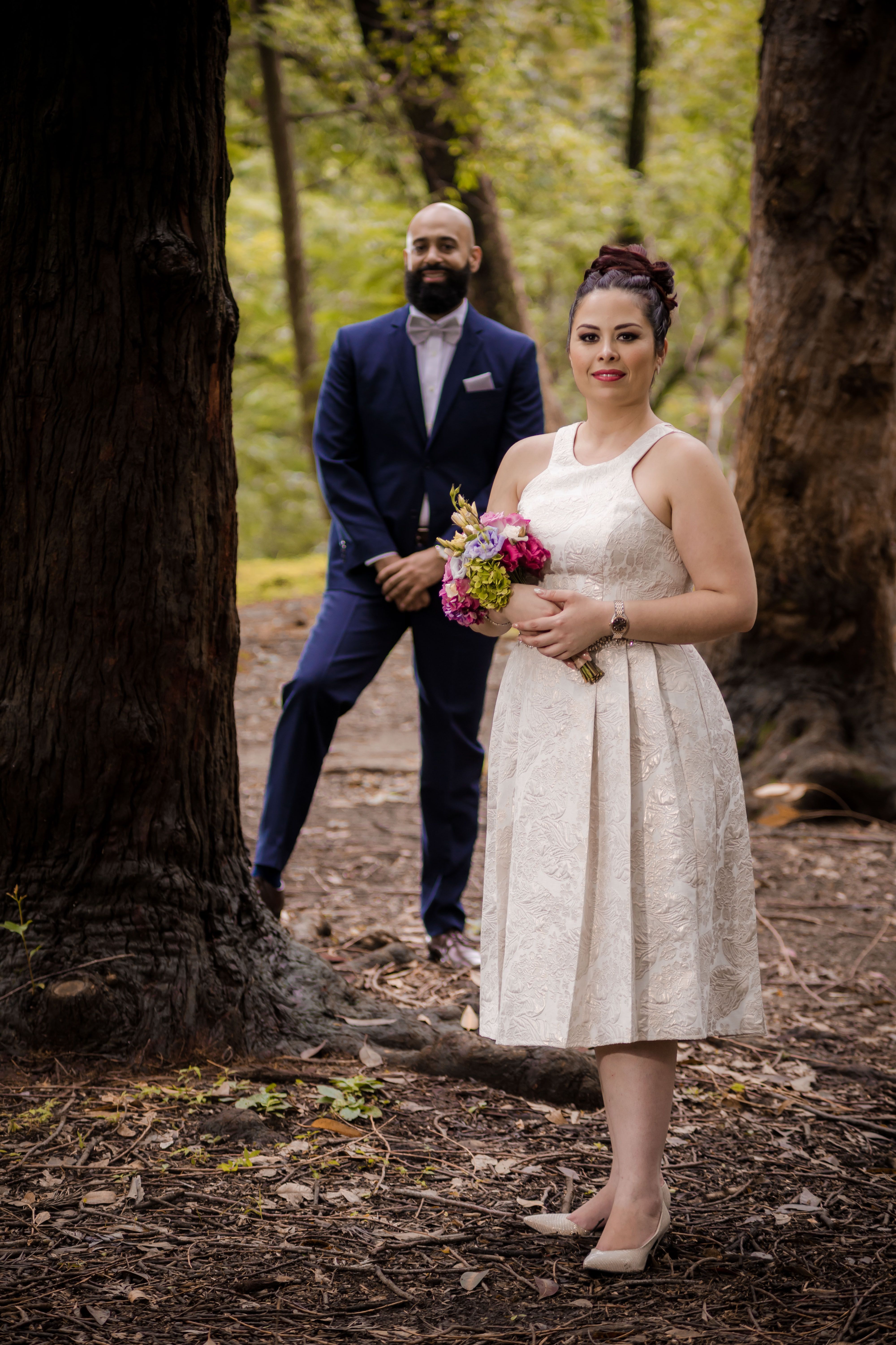 Bride and Groom Standing Near Tree Trunk · Free Stock Photo