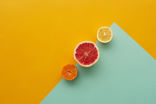 葡萄柚、柠檬和橘子两半的顶视图，置于五颜六色的几何背景上