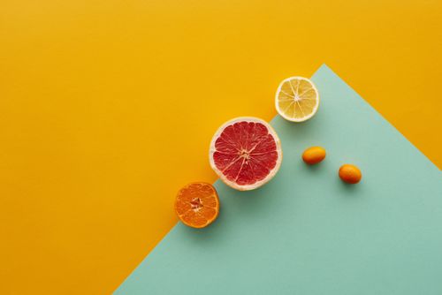 Free Creative display of sliced citrus fruits on a yellow and teal background showcasing fresh and vibrant colors. Stock Photo