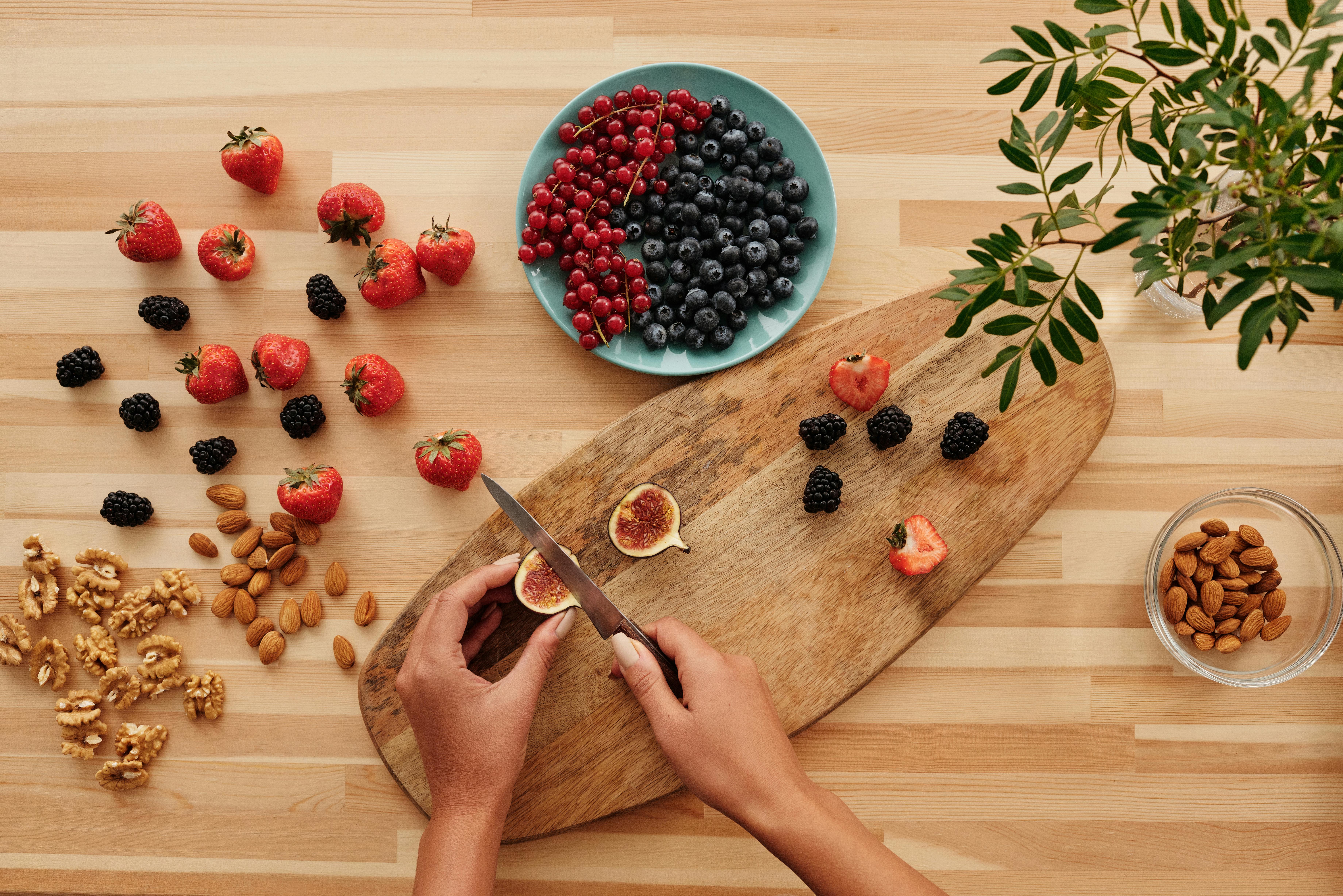 person holding stainless steel knife slicing red and white fruit