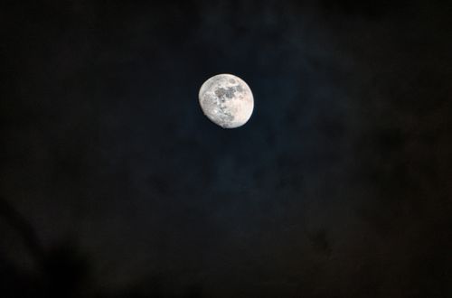 Free From below of majestic white moon with spots in dark black night sky Stock Photo