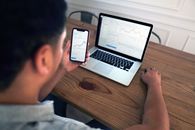 Person Holding Iphone 6 Near Macbook Pro