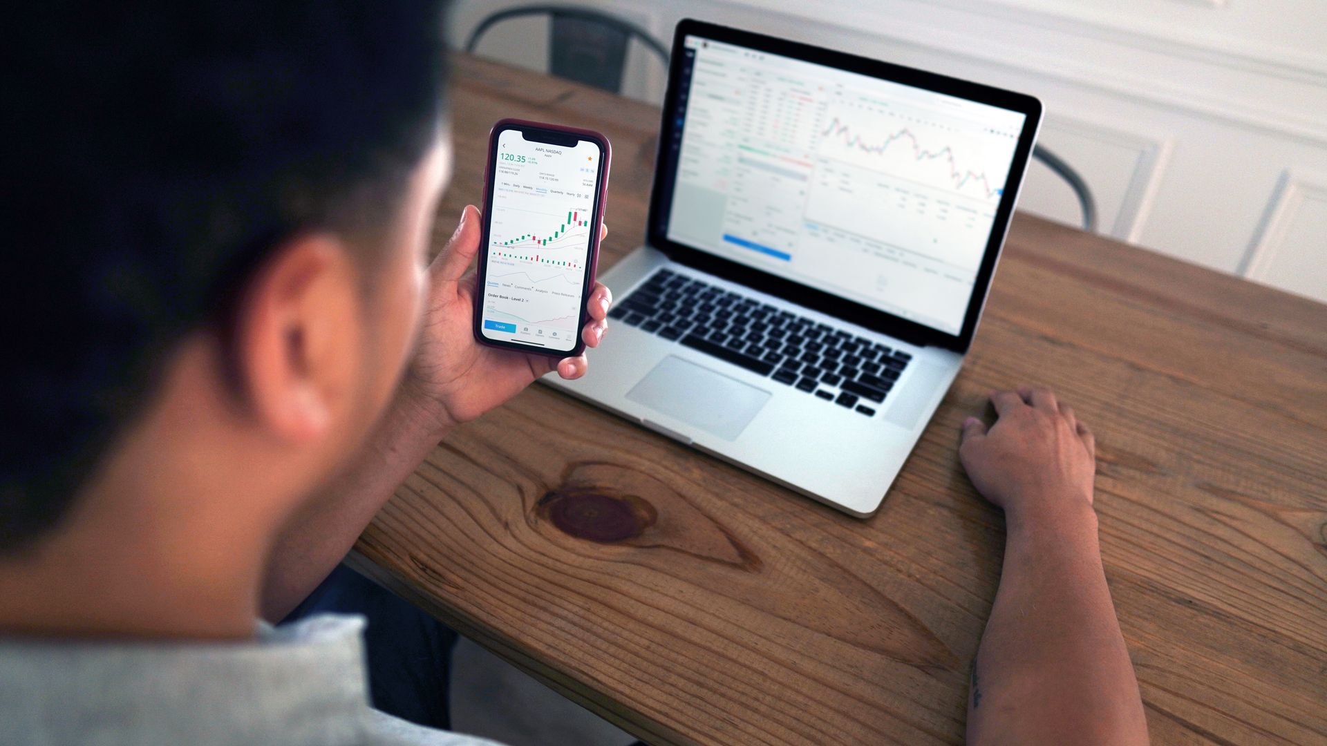 Modafinil for Stock Traders: The Ultimate Guide Individual reviewing stock market trends using a laptop and smartphone at a wooden table — modafinil for stock traders