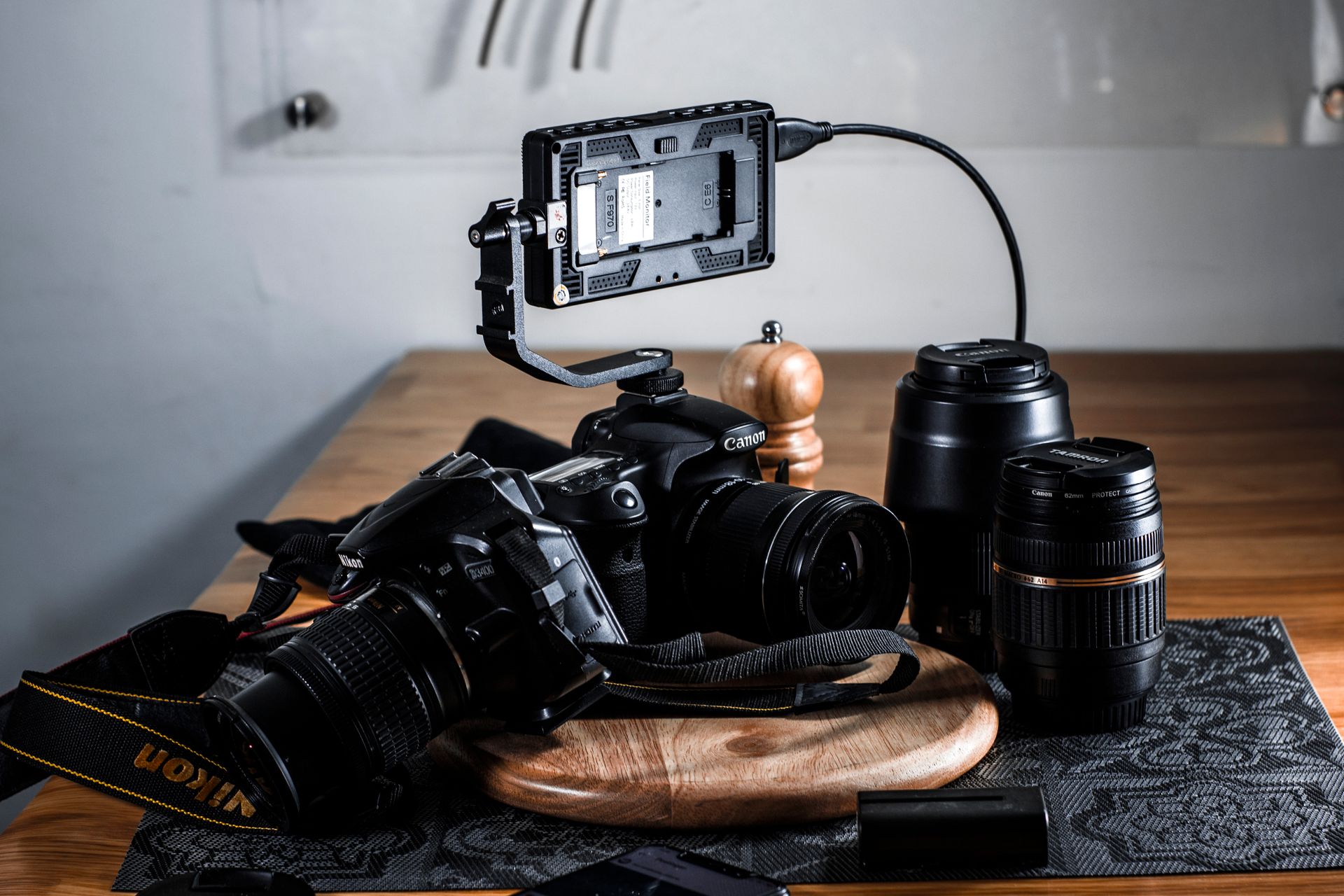 Close-up of professional photography gear including lenses and a camera setup on a wooden table.