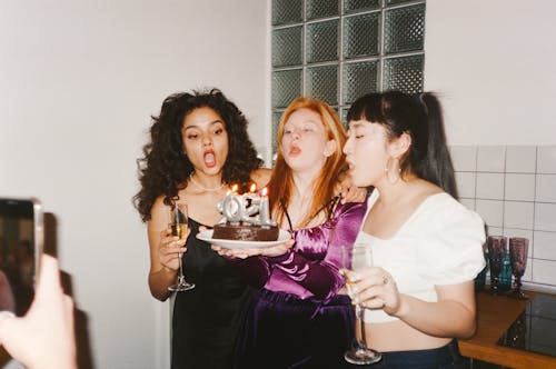 Women Blowing the Candles on a Cake Together