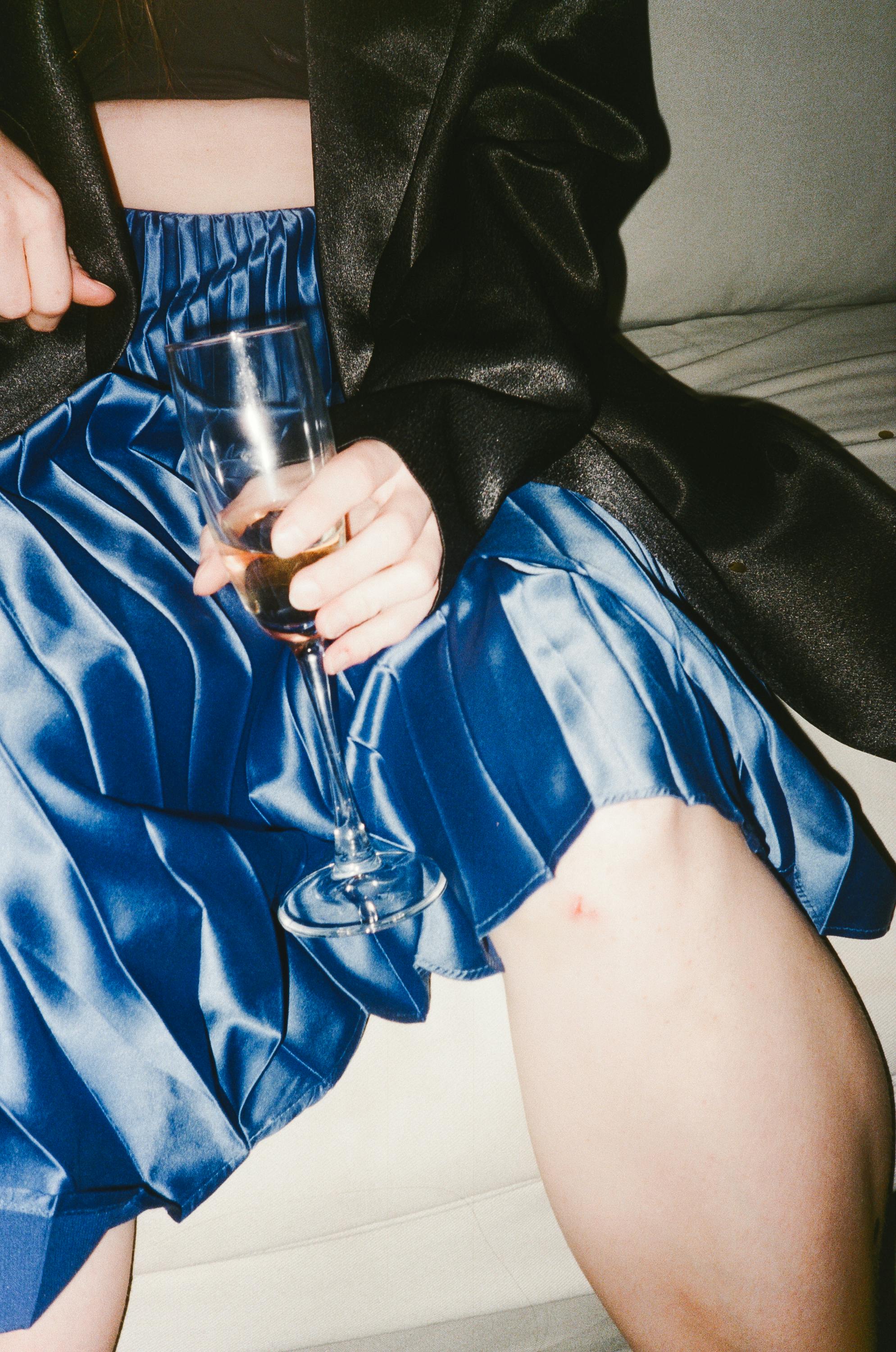 特写一位身着优雅蓝色服装、手持香槟杯的人物，非常适合生活方式主题