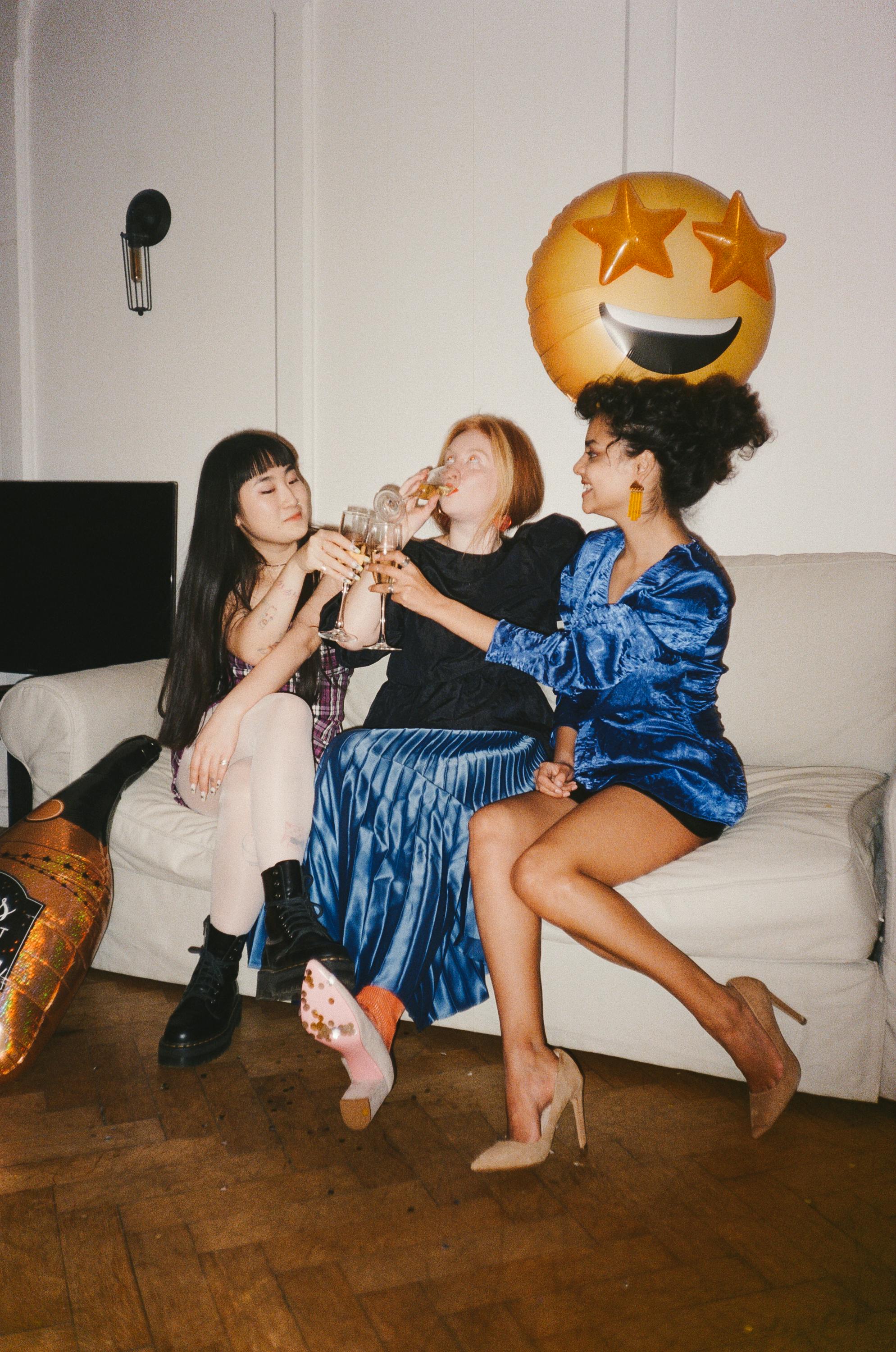 women drinking together while sitting on a sofa