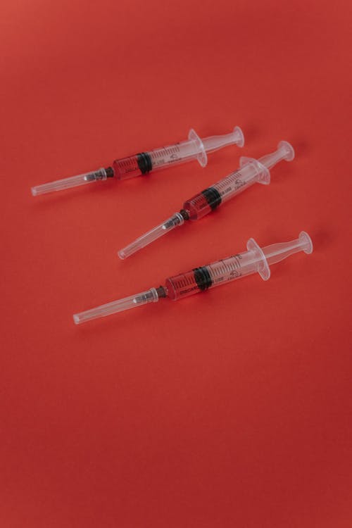Close-Up Shot of Syringes on a Red Surface