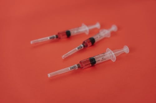 Close-Up Shot of Syringes on a Red Surface