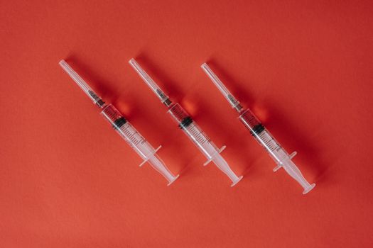 三个注射器排列在红色表面上，展示了带有复制空间的医疗设备