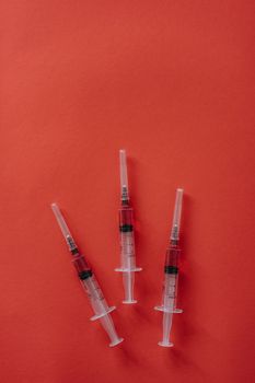 三个注射器摆放在充满活力的红色表面上，展示着医疗设备