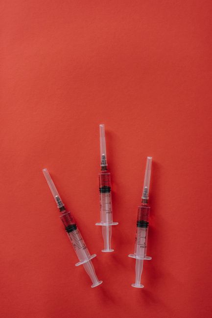 Three syringes placed on a vibrant red surface, showcasing medical equipment. Three syringes placed on a vibrant red surface, showcasing medical equipment.