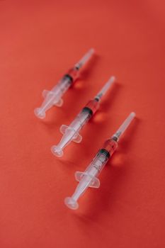 三个注射器排列在醒目的红色表面上，象征着医学主题