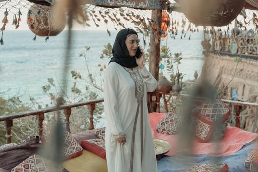 A woman in traditional attire talks on her phone in a beautifully decorated setting by the sea.