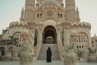 Woman in Black Dress Standing in Front of White Concrete Building