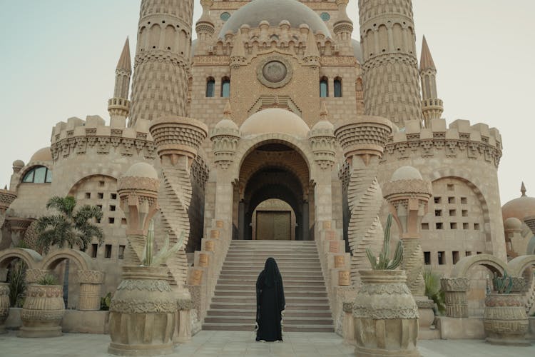 A Woman Wearing A Black Robe Standing In Front Of Al Sahaba Mosque