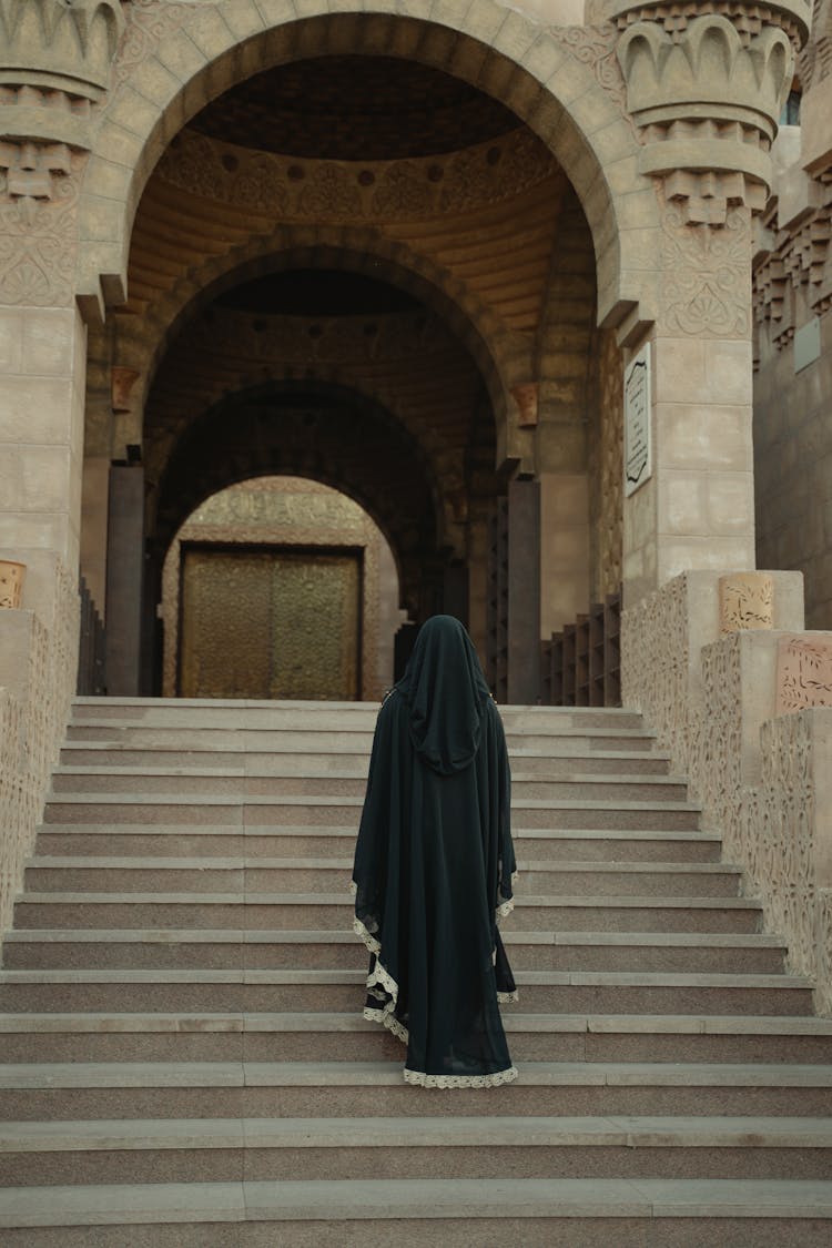 A Person In A Black Robe Walking Up The Stairs