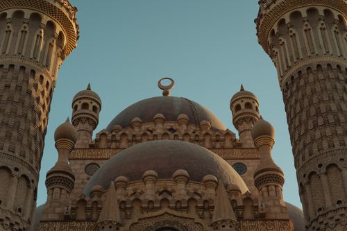 Free A stunning view of an ornately designed mosque with detailed domes and twin minarets under a clear sky. Stock Photo