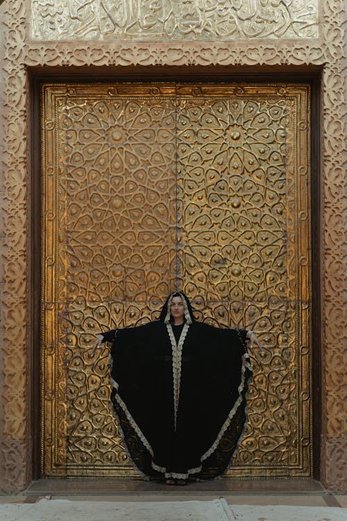 Woman In Black Abaya Standing Beside A Golden Door