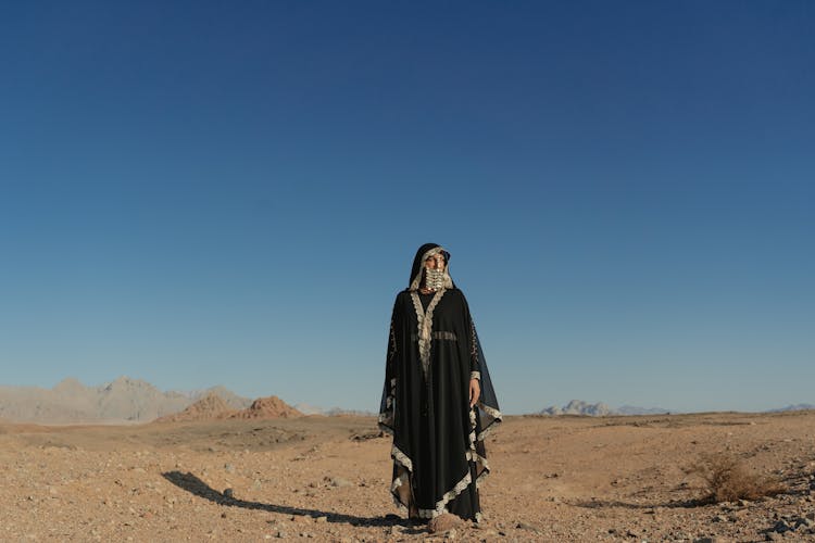 A Woman In Black Abaya Standing On The Desert